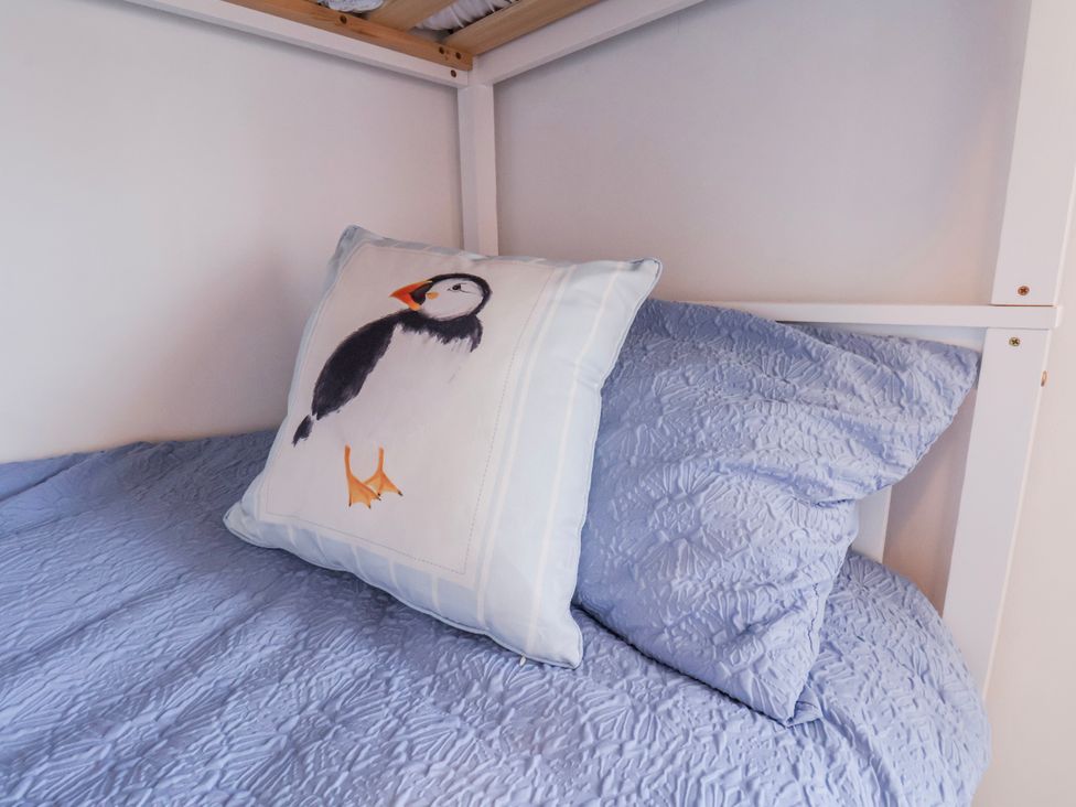 A bed with a blue bedspread and a pillow featuring a puffin design at 1 West Ville Mews York