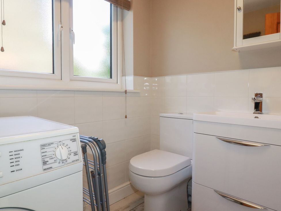A bathroom with a washing machine, toilet, and sink at Stowaway Cottage in Padstow