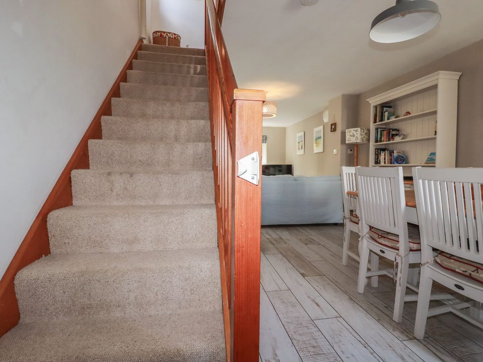 A dining room with a staircase and furniture at Stowaway Cottage in Padstow