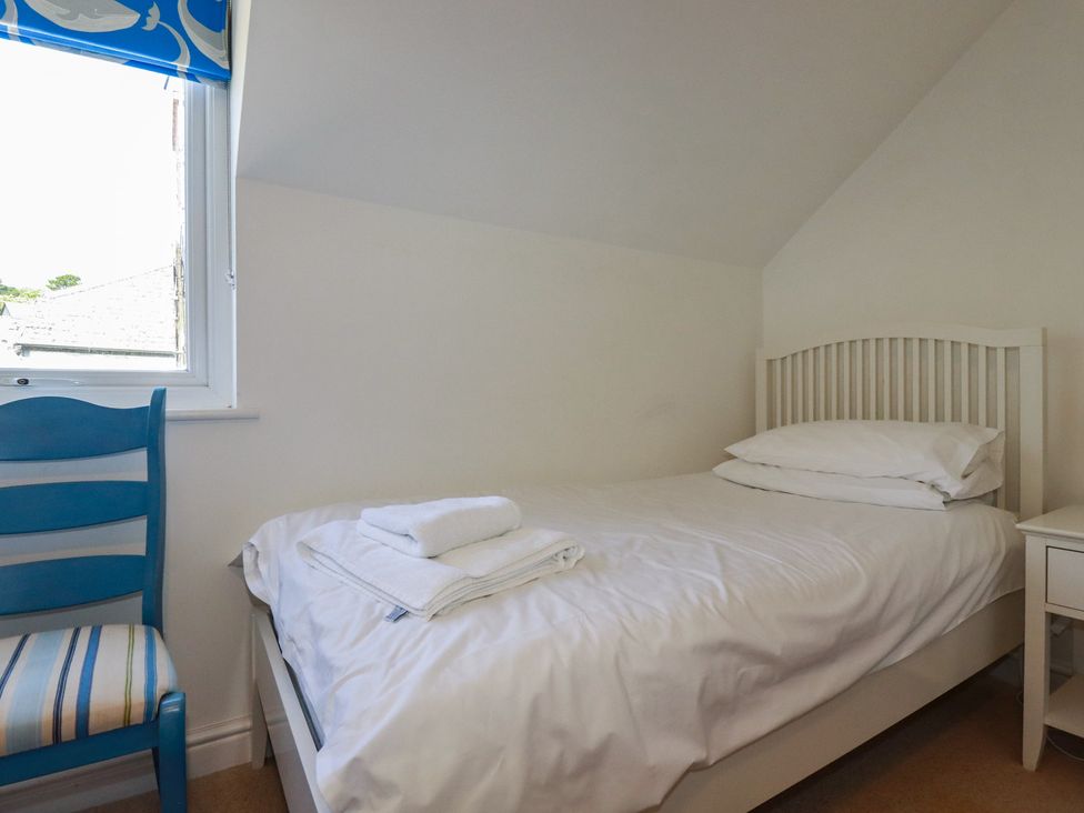 A bedroom with a bed and a blue chair at Stowaway Cottage in Padstow