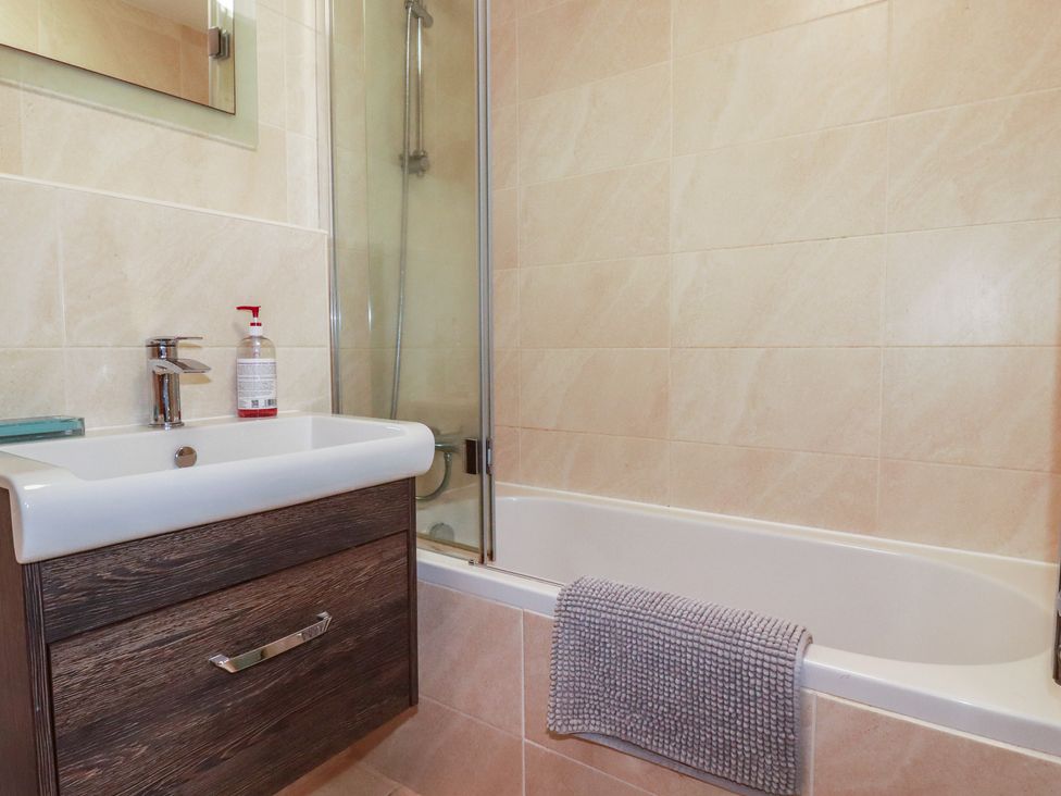 A bathroom with a sink, bathtub, and shower at Stowaway Cottage in Padstow
