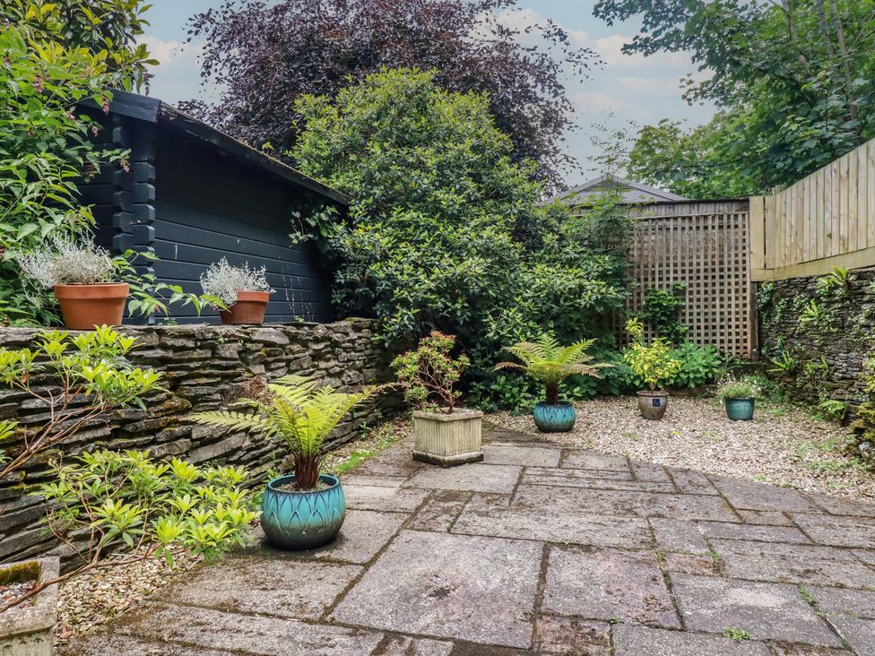 A garden with stone wall and potted plants at Stowaway Cottage in Padstow