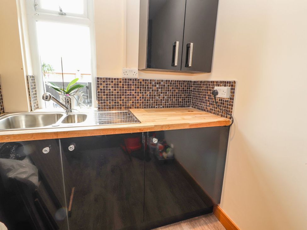 A kitchen with a sink and black cabinets at The Wendover in Abergele