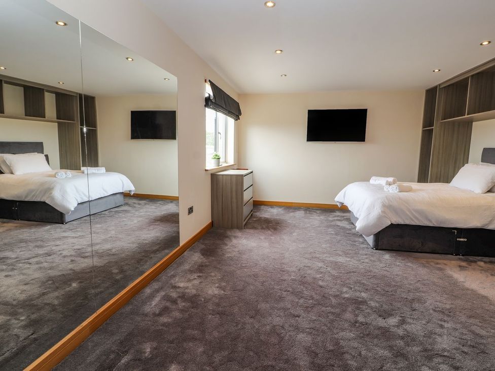 A bedroom with two beds and a mirror at The Wendover in Abergele