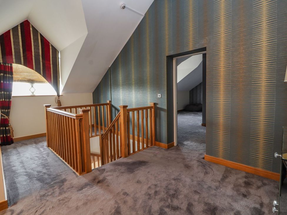 A landing area with a wooden staircase and door at The Wendover in Abergele