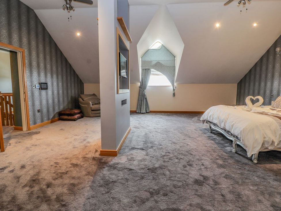 A bedroom with a bed, armchair and curtain at The Wendover in Abergele