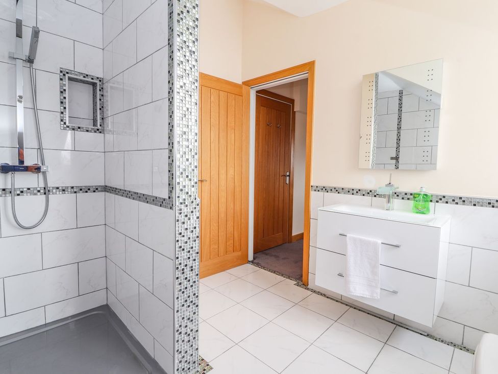 A bathroom with shower, washbasin and mirror at The Wendover in Abergele