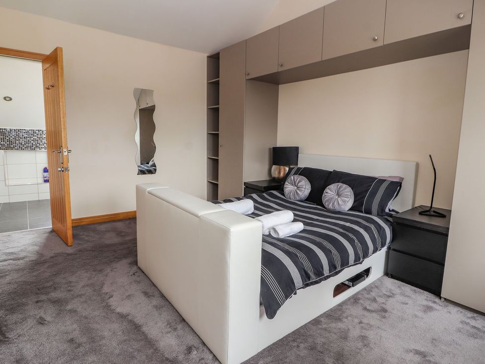 A bedroom with a bed and mirror at The Wendover in Abergele