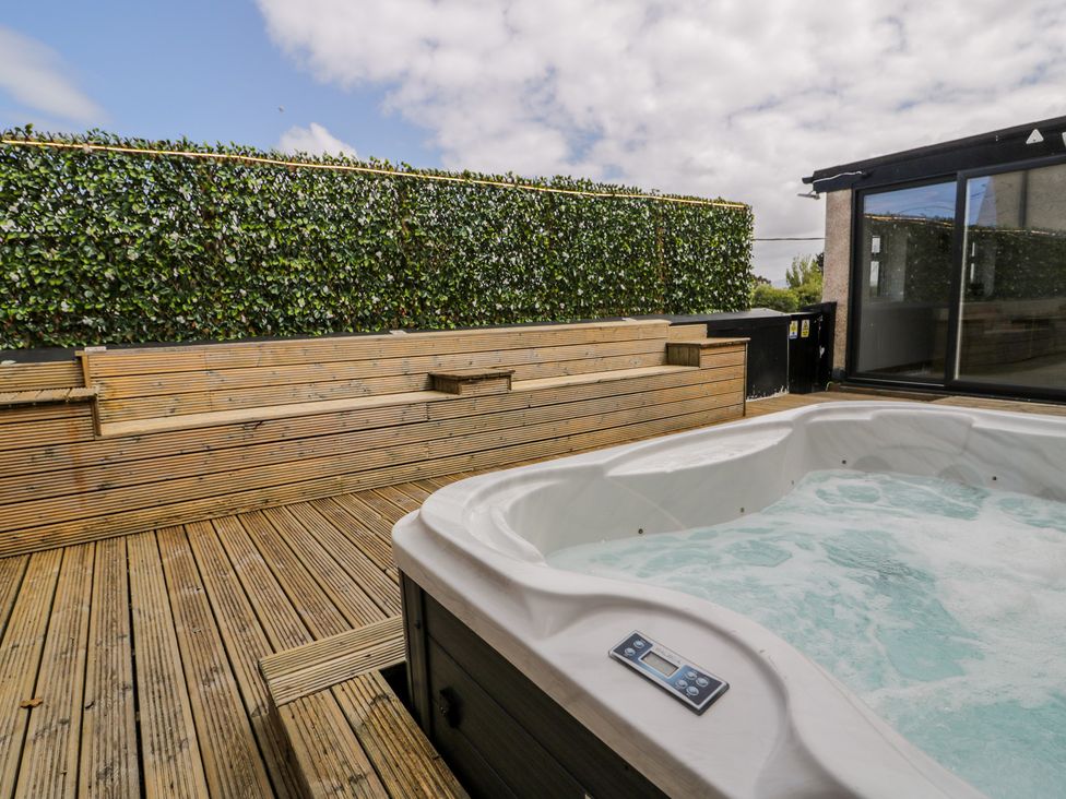 An outdoor area with a hot tub and wooden seating at The Wendover in Towyn