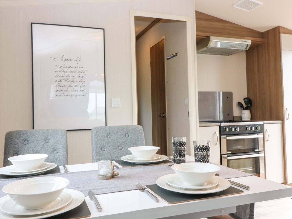 A dining room with table set for dinner and kitchen appliances at 18 Eden Heights in St Andrews