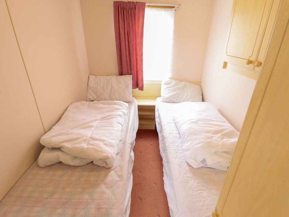 A bedroom with two single beds and a window at Number 9 Skegness