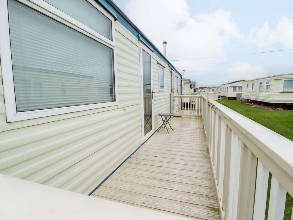 A mobile home with a deck and chair at Number 9 Skegness