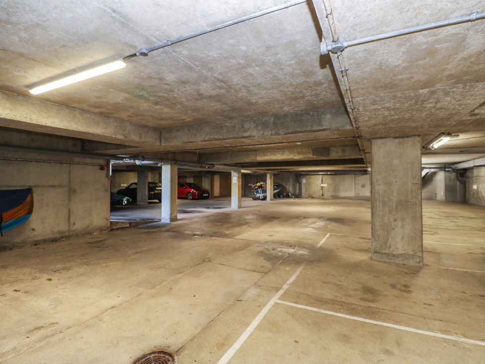 A parking garage with vehicles and overhead lighting at Anchorage House Seaview