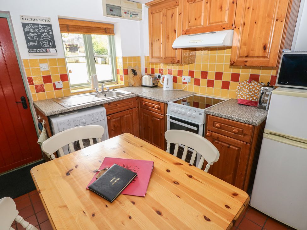 A kitchen with wooden furniture and appliances at Swallow Cottage in Cowbridge