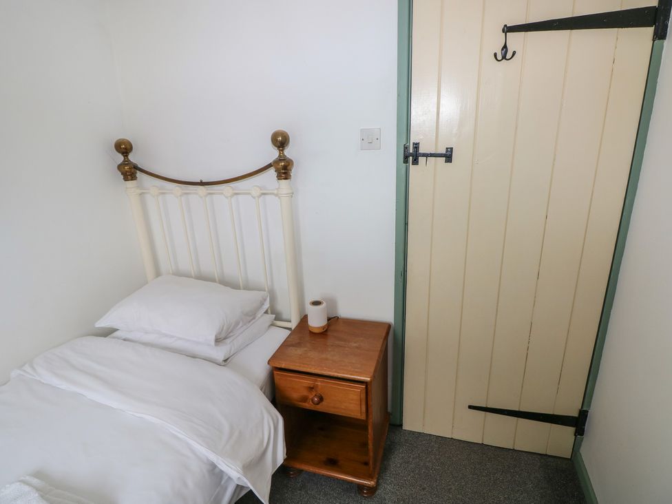 A bedroom with a bed and a nightstand at Swallow Cottage in Cowbridge