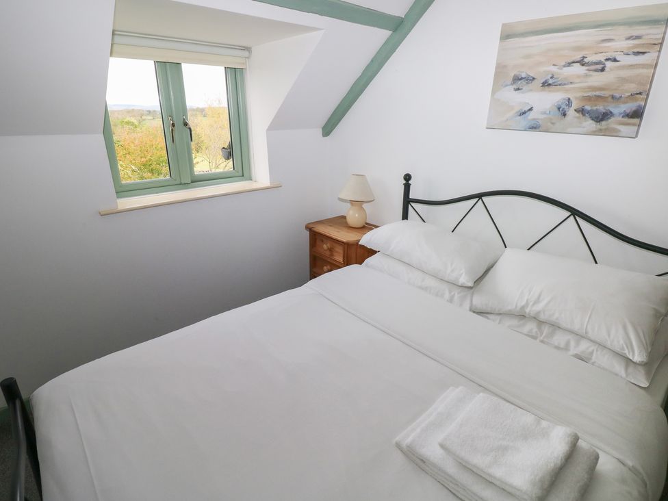 A bedroom with a bed and window at Swallow Cottage in Cowbridge