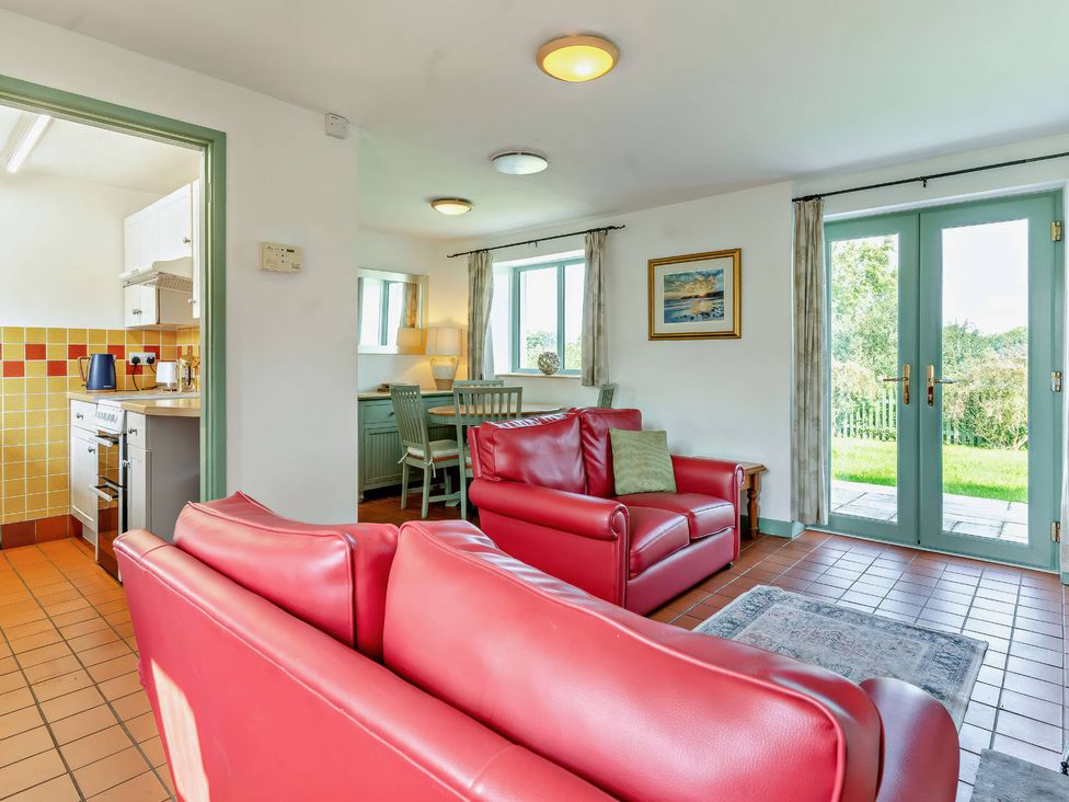 A living room with a red sofa and dining area at Wren Cottage in Cowbridge