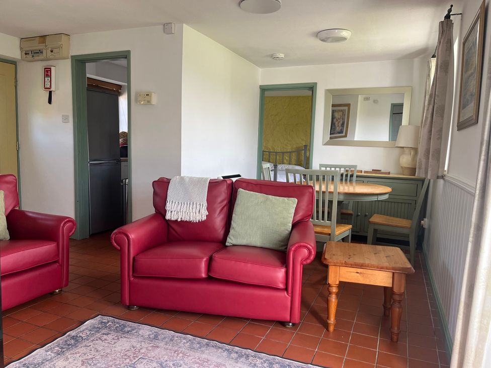 A living room with a red sofa and dining table at Wren Cottage in Cowbridge