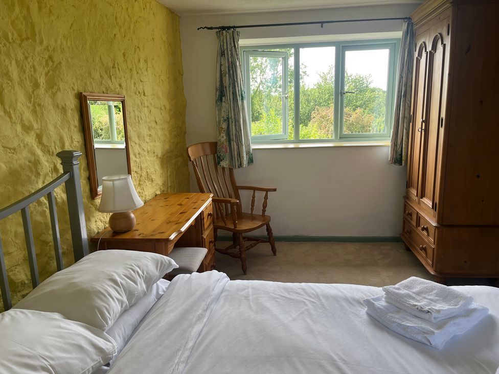 A bedroom with a bed, dresser, chair, and window at Wren Cottage in Cowbridge