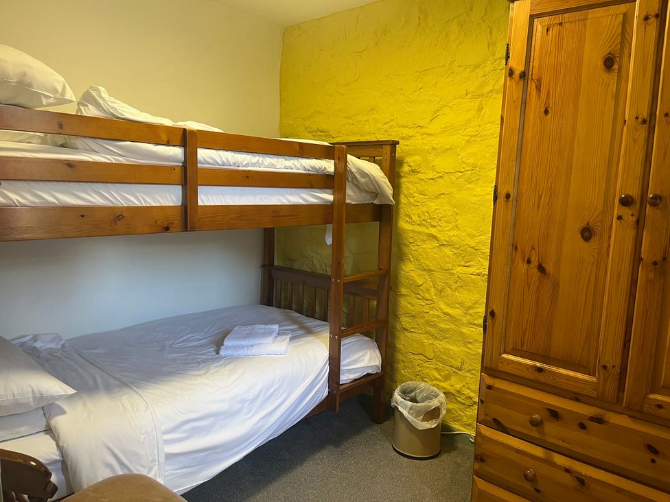 A bedroom with a bunk bed and a single bed at Wren Cottage in Cowbridge