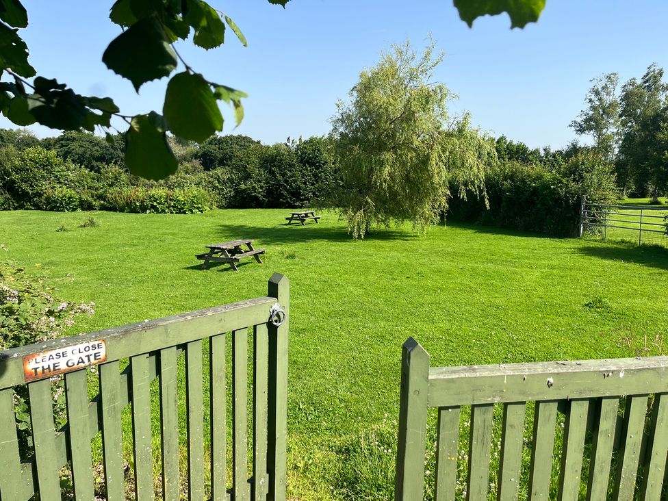 A garden with picnic tables and a gate at Wren Cottage in Cowbridge