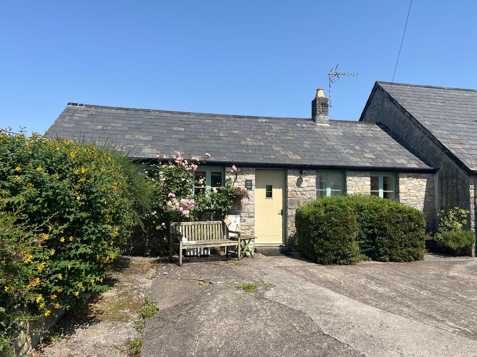 A cottage with a door and a bench at Wren Cottage in Cowbridge