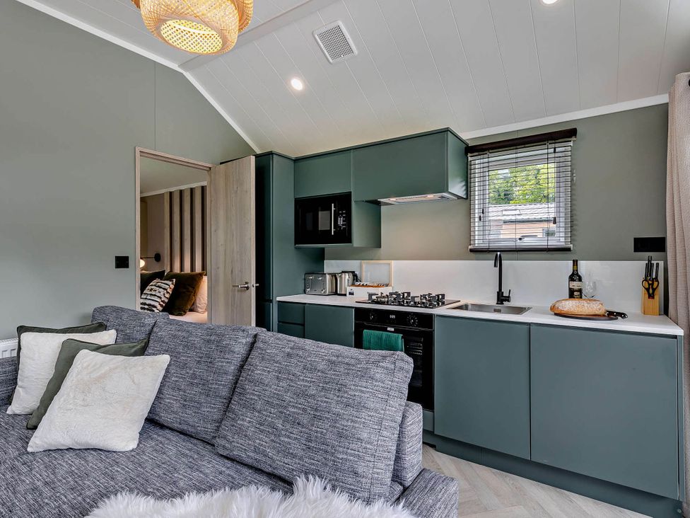 A kitchen with cabinets and a sofa at Prion 1.0 Pet in Llandyrnog