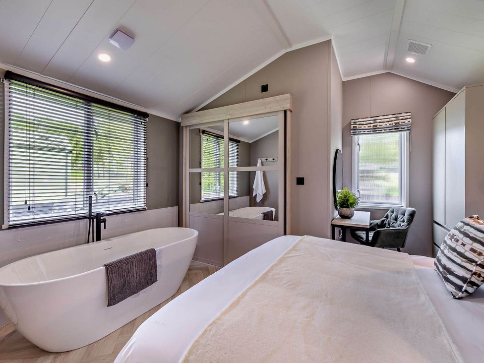 A bedroom featuring a bathtub and a workspace at Prion 1.0 Pet in Llandyrnog
