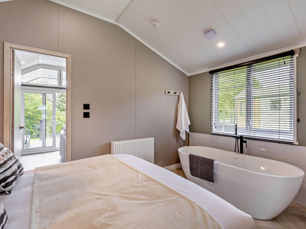 A bedroom with a bathtub and a window at Prion 1.0 Pet in Llandyrnog