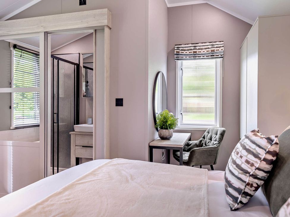 A bedroom with a bed and a wooden table at Prion 1.0 Pet in Llandyrnog