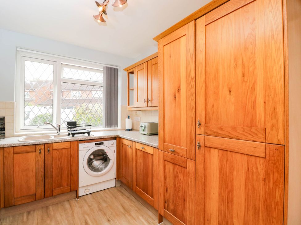 A kitchen with wooden cabinets and a washing machine at 3 Station Road in Weston-Super-Mare
