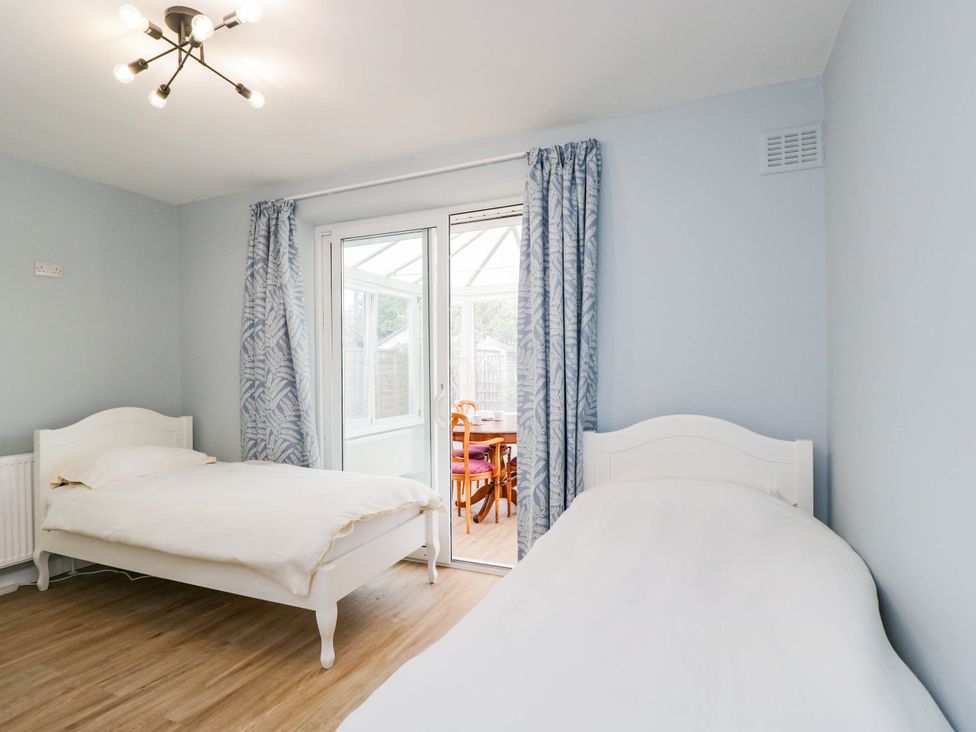 A bedroom with two beds and a doorway to a conservatory at 3 Station Road Weston-Super-Mare