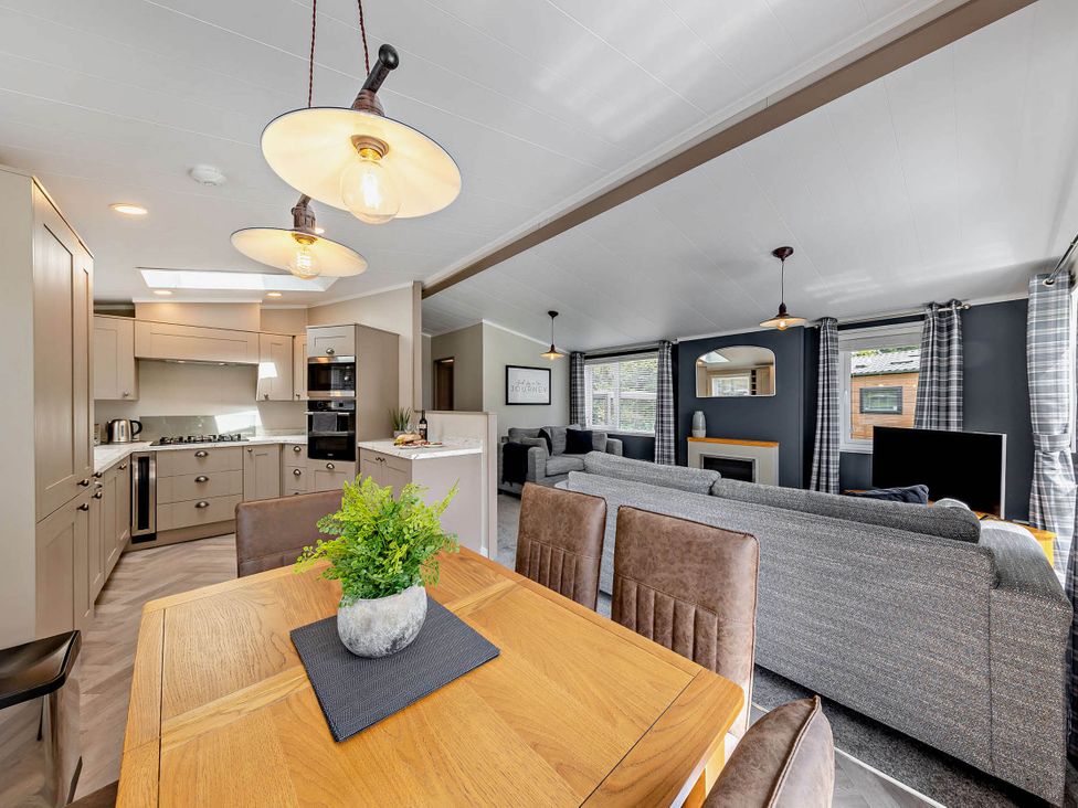 A living room and kitchen area with a dining table and modern appliances at Elwy 3.0 Pet in Llandyrnog