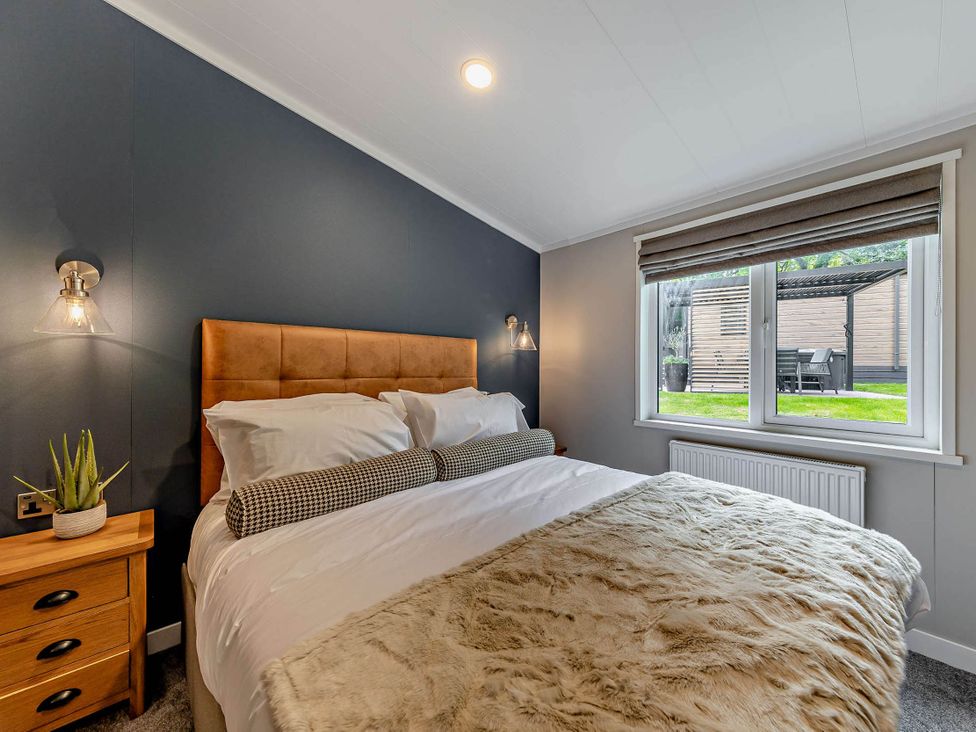A bedroom with a bed and window overlooking a garden at Elwy 3.0 Pet Llandyrnog
