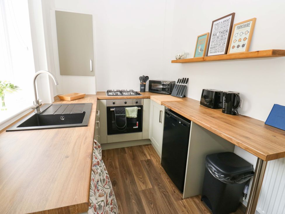 A kitchen with a stove, sink, microwave, and refrigerator at Saltaire House in Saltaire
