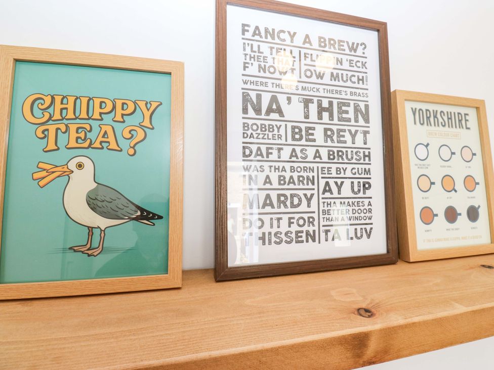 Framed artworks on a wooden shelf at Saltaire House in Saltaire