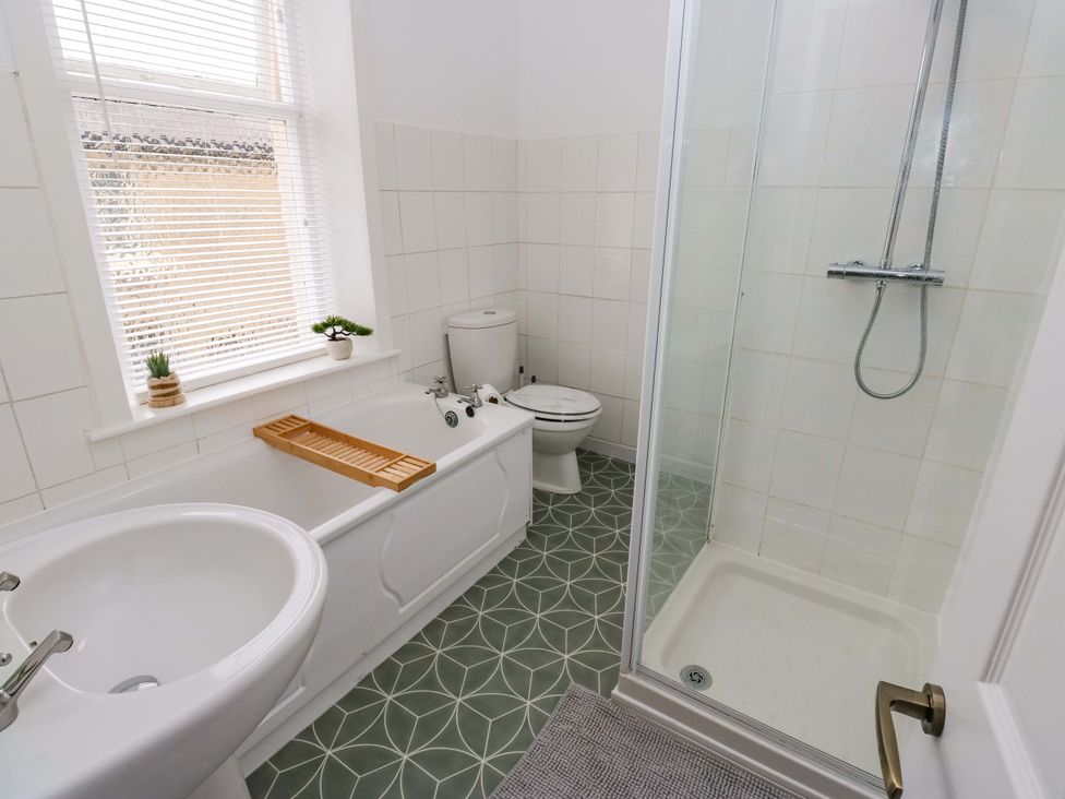 A bathroom with a bathtub, shower, toilet and sink at Saltaire House, Saltaire