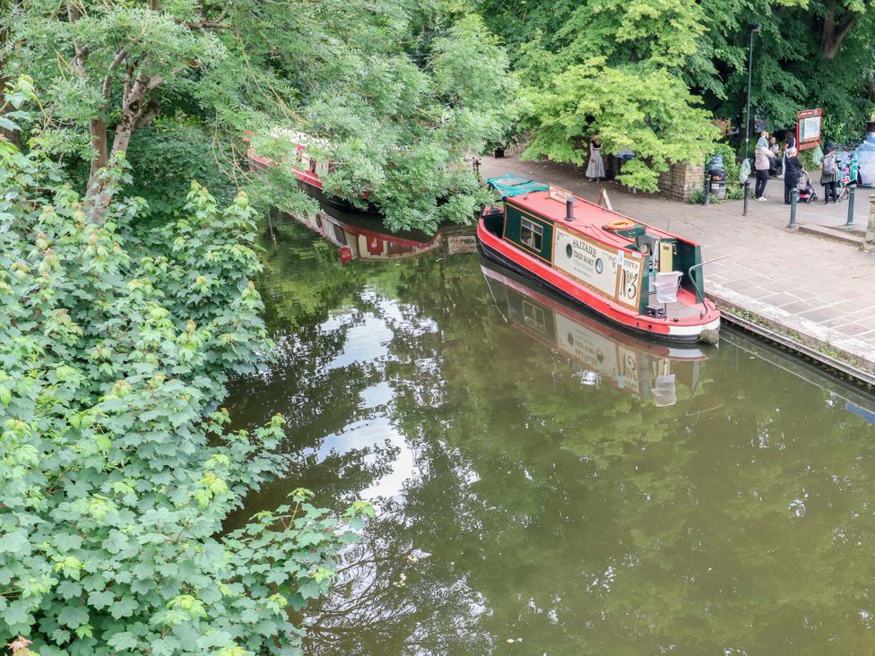 A canal with a boat and people walking along a pathway at Saltaire House in Saltaire