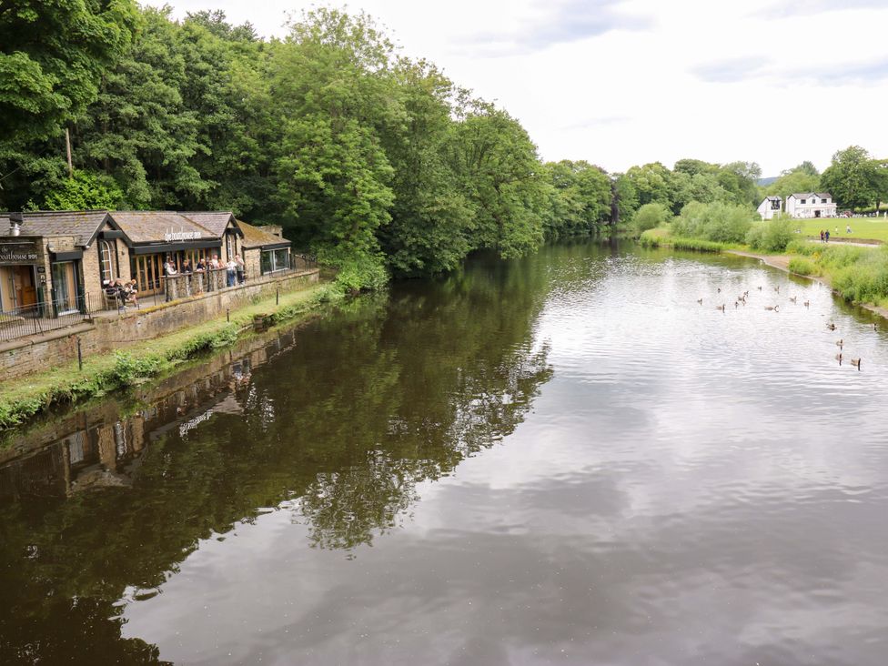 A river with ducks and a restaurant along the bank at Saltaire House in Saltaire