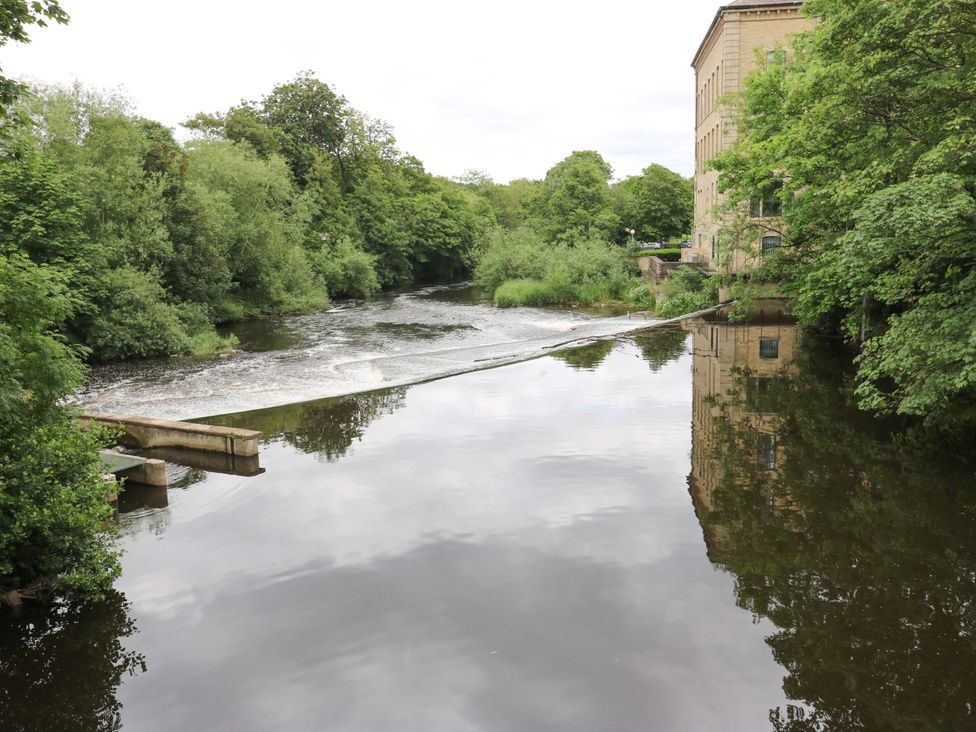 A river with trees and a building in Saltaire House in Saltaire
