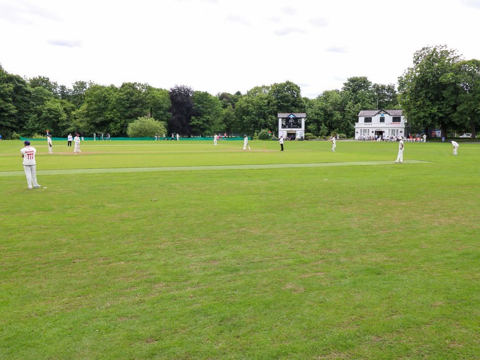 A cricket match taking place on a grassy field at Saltaire House in Saltaire