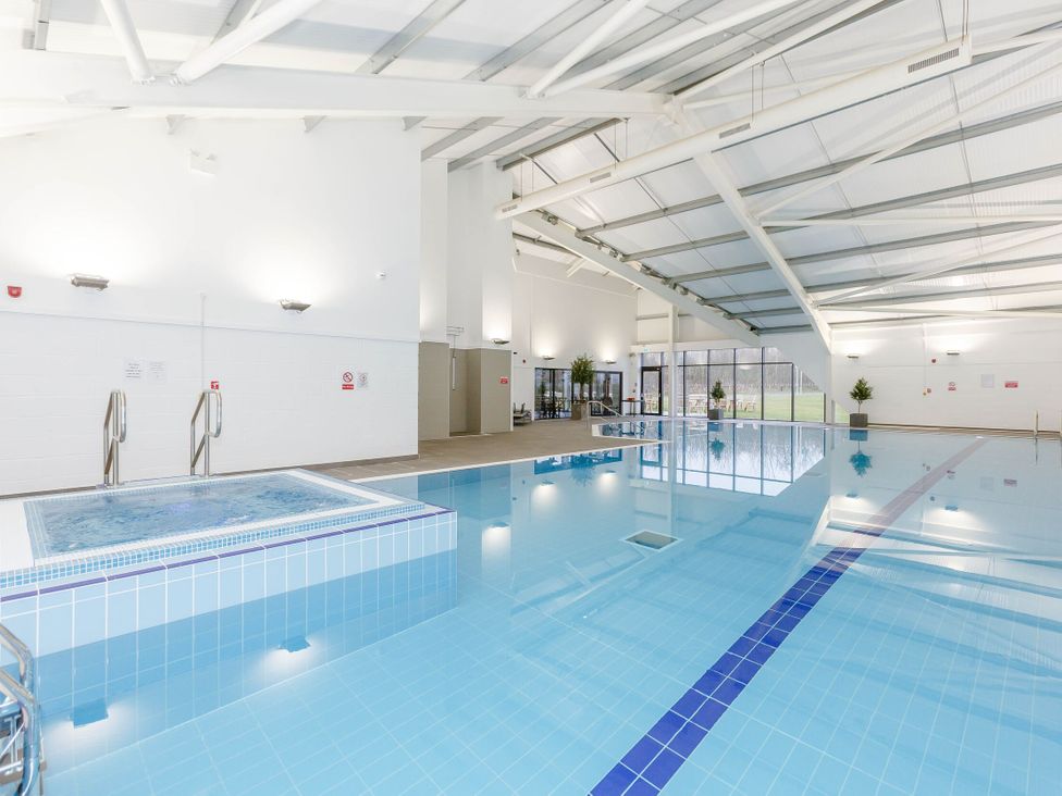 A swimming pool with a jacuzzi and windows at Pine Lodge Spa Pet Thirsk