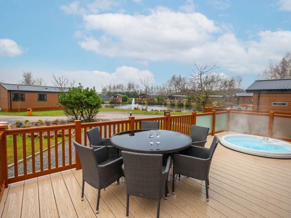 An outdoor space with a table and chairs plus a hot tub at Laurel Waterside Spa Carlton Miniott near Thirsk