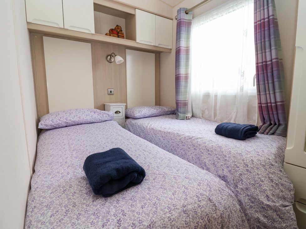 A bedroom with two beds and a bedside table at 15 Cherry Tree walk, Rhyl