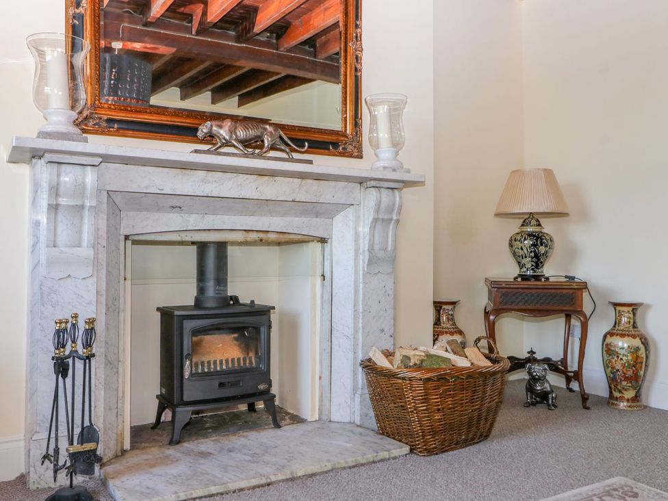 A sitting room with a fireplace and a basket of firewood at Tuft House in Hovingham