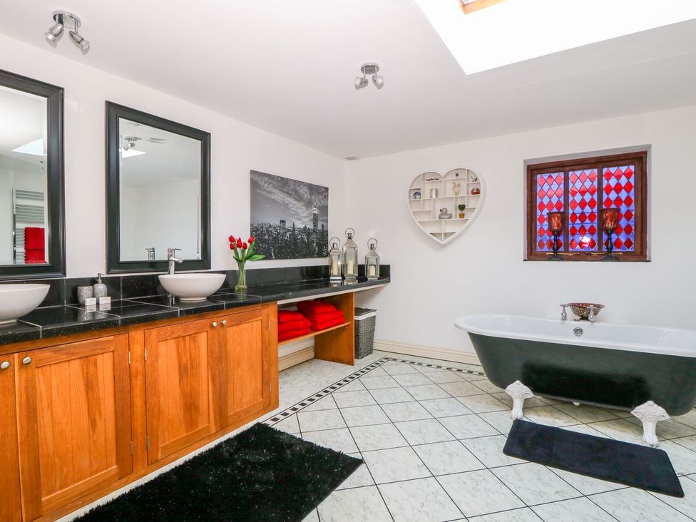 A bathroom featuring a bathtub, sinks, and mirrors at Tuft House in Hovingham
