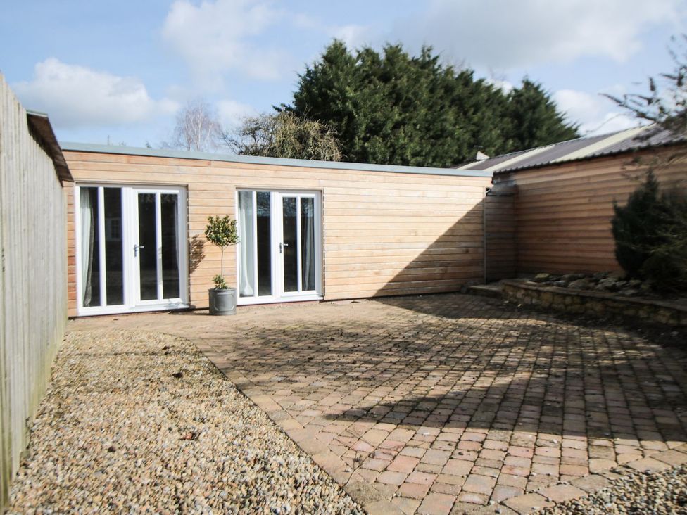 A garden area with brick paving and glass doors at Tuft House in Hovingham