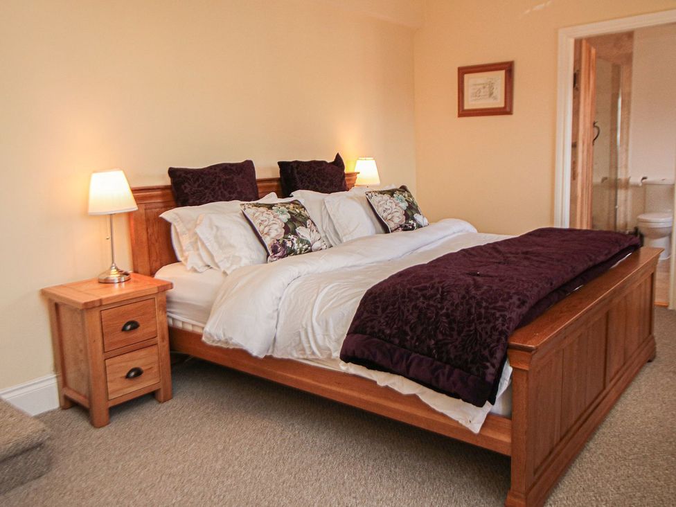 A bedroom with a wooden bed and nightstand at Tuft House in Hovingham