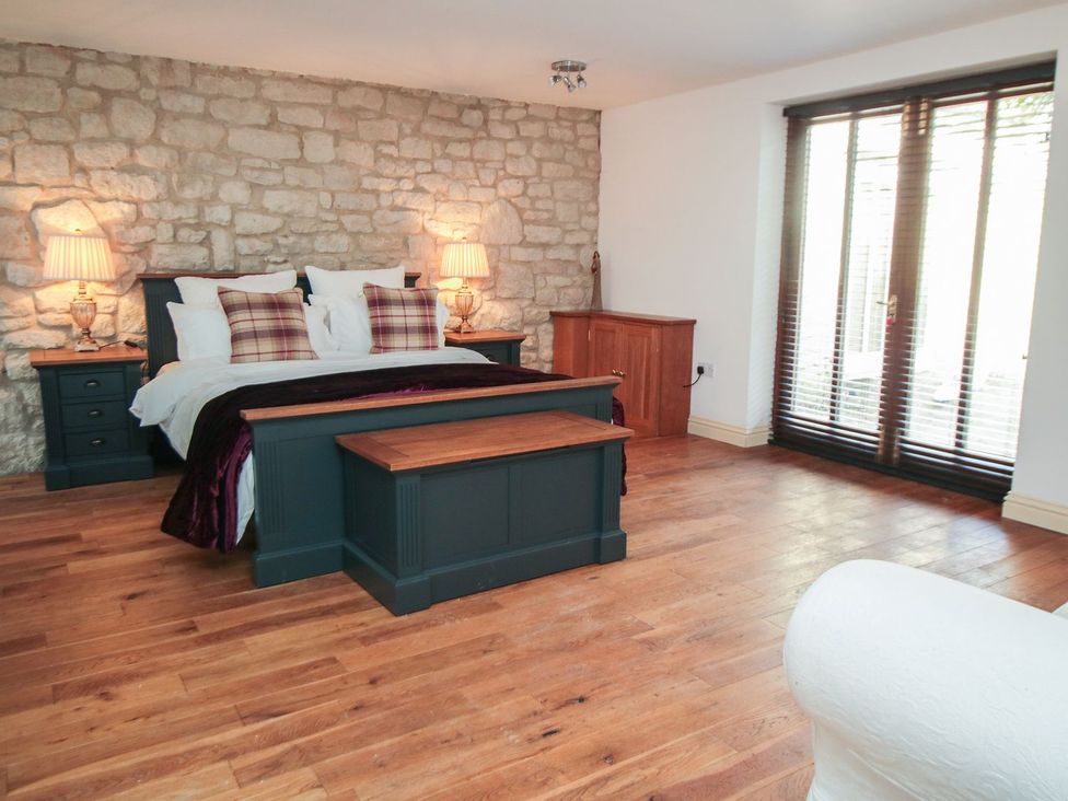 A bedroom with a bed and wooden furniture at Tuft House in Hovingham