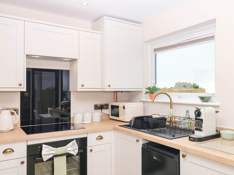 A kitchen with white cabinets and appliances at Little Folley in Whitestone near Tedburn St Mary
